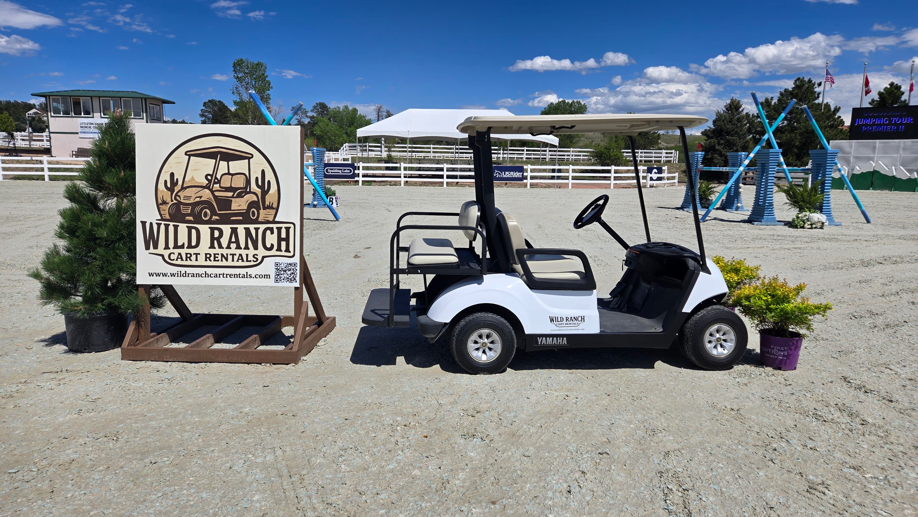 A Wild Ranch golf cart parked beside the company's branded sign at a Colorado equestrian event